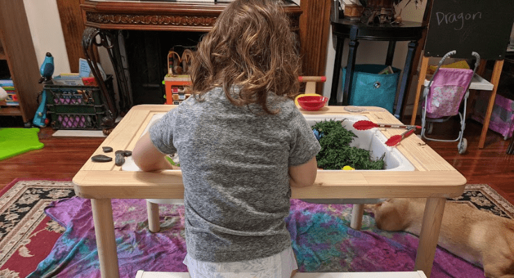 toddler playing at sensory bin table