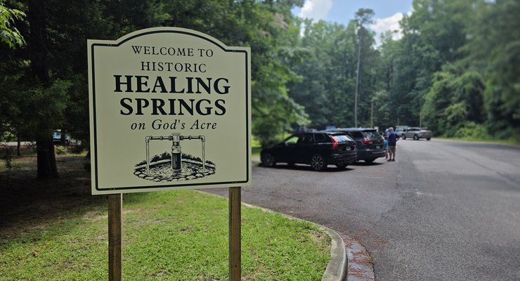 Welcome to Historic Healing Springs on God's Acre sign with parking area and trees in Blackville, SC