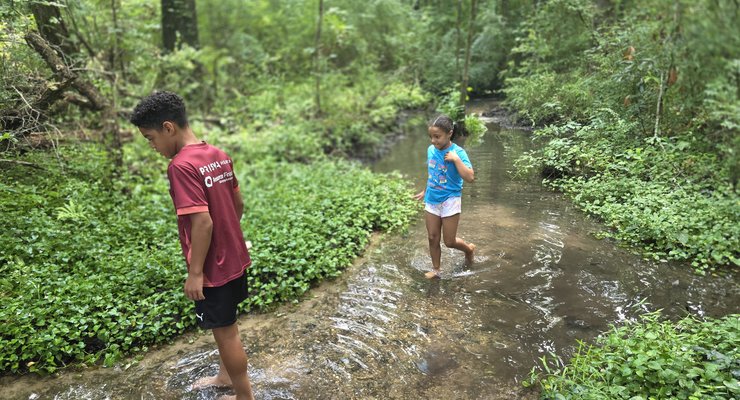 Children wading barefoot in the shallow stream at God's Acre Healing Springs in Blackville, SC