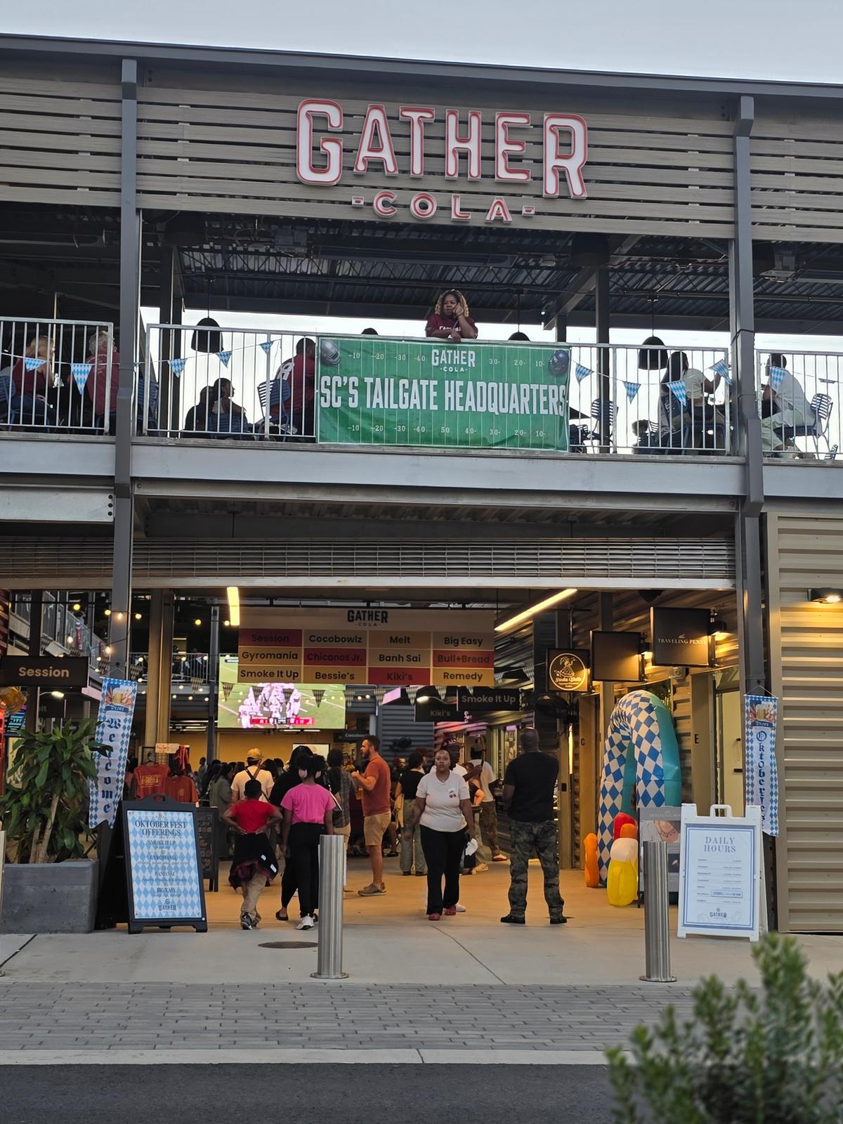 The entrance to Gather COLA with the vendor board and a game-day tailgate banner