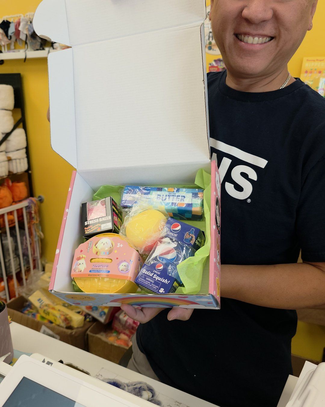 Smiling man holding open a Linga Binga box filled with squishy toys